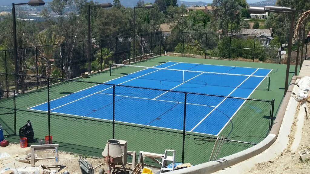 Black chain link fencing around a backyard tennis court