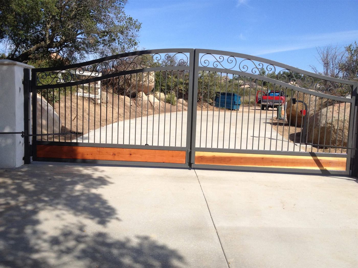 Custom wrought iron driveway gate with wood panel inserts