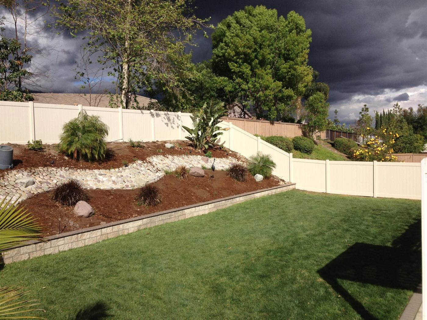 Two-tone vinyl privacy fence along a garden path